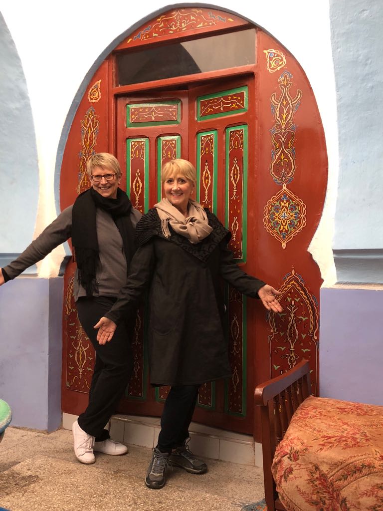 Two female solo travelers in front of an ornate door in Morocco on AdventureWomen trip to Morocco