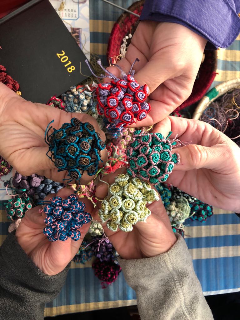 women displaying colorful cherry buttons that they made during their trip