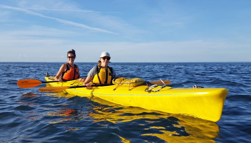 Two women kayaking in a bright yellow kayak