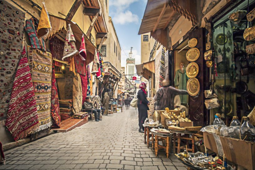 Cobblestoned streets of Fez with local rugs, baskets and spices on display for sale