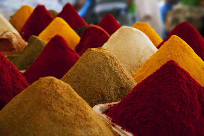 A colorful mound of different Moroccan spices in colors of red, orange and brown hues