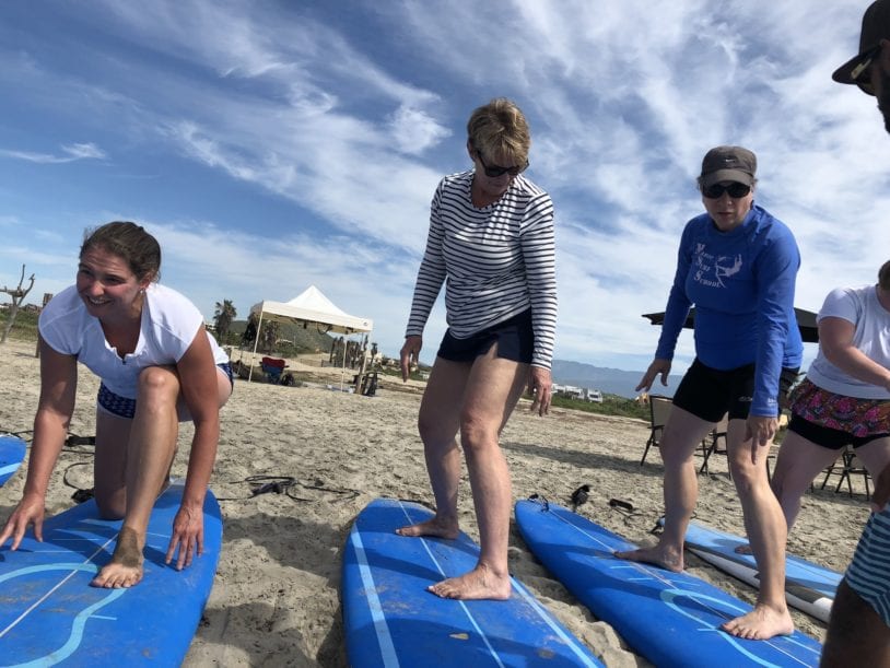 Three women learning surfing position in advance of water instruction