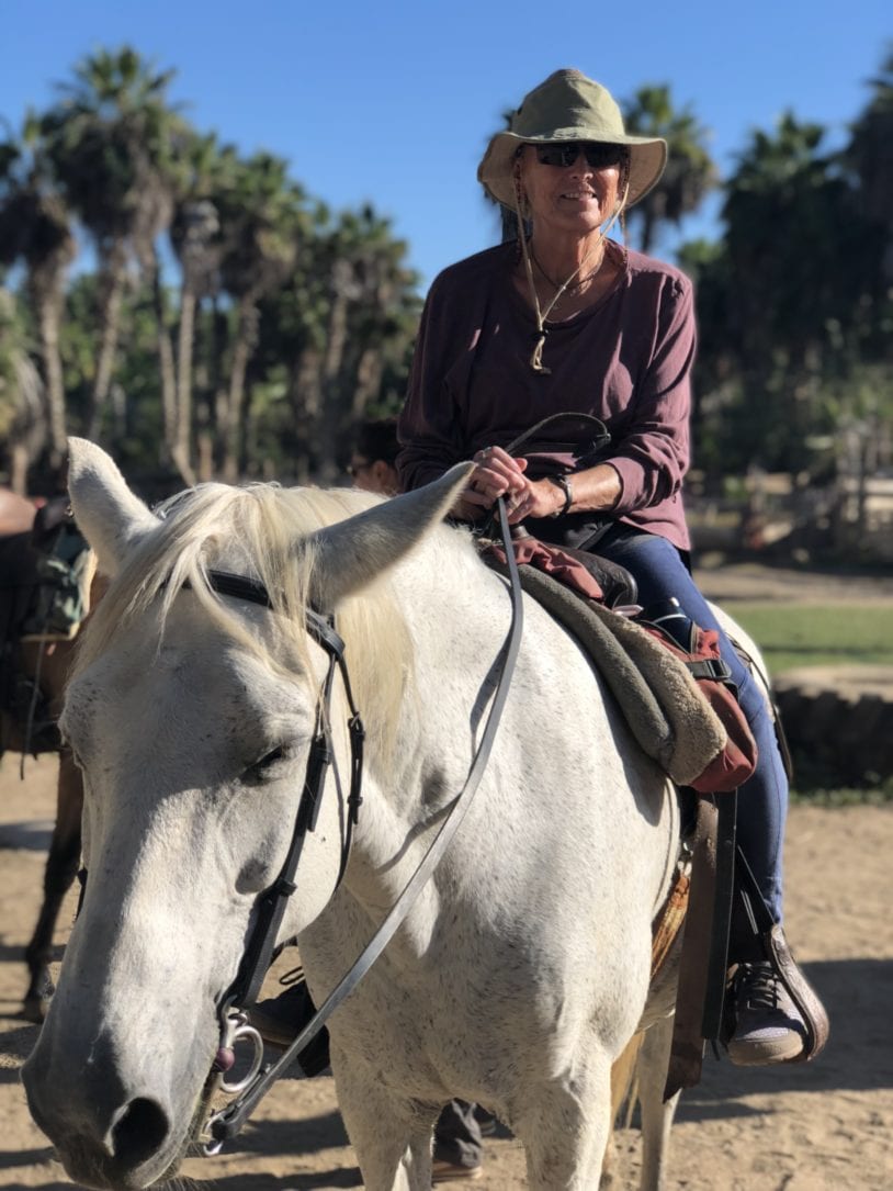 A woman enjoying a horseback ride on the beautiful beaches of Baja