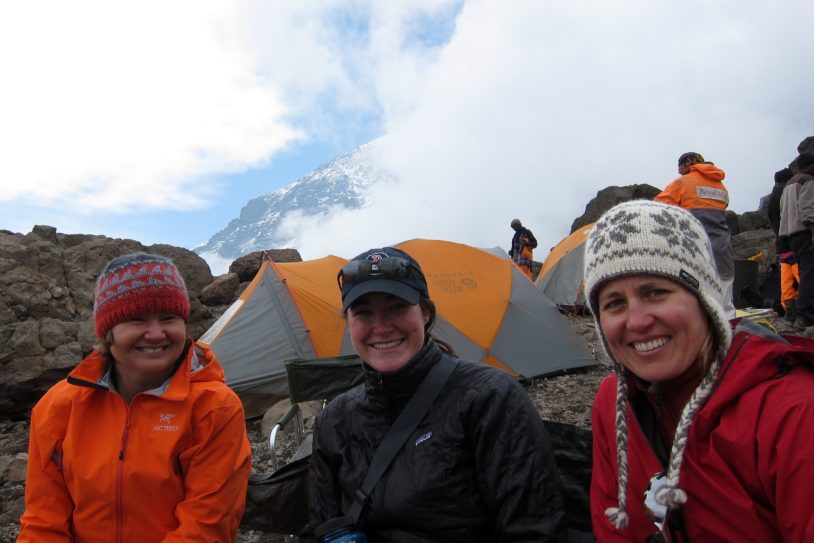 Smiling hikers take photo next to tents