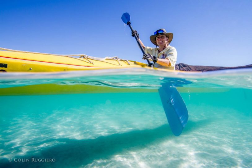Adventurous woman kayaking in crystal clear ocean water in Baja