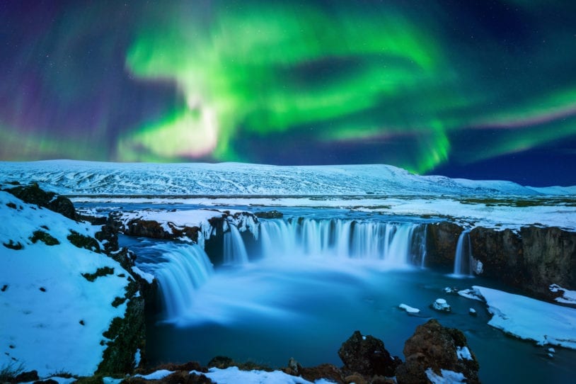 The Northern Light green glow at Godafoss waterfall in winter Iceland with AdventureWomen.