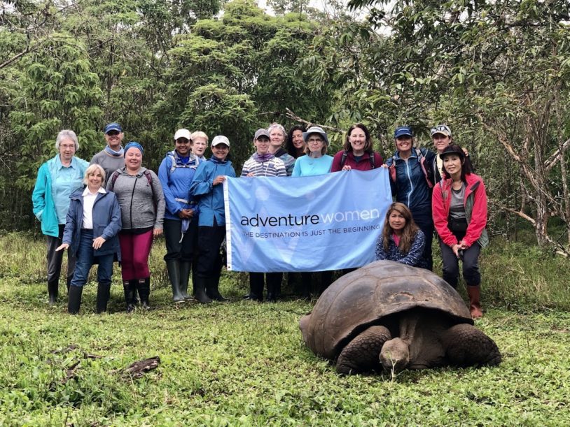 Adventure Women holding their flag next to a huge tortoise