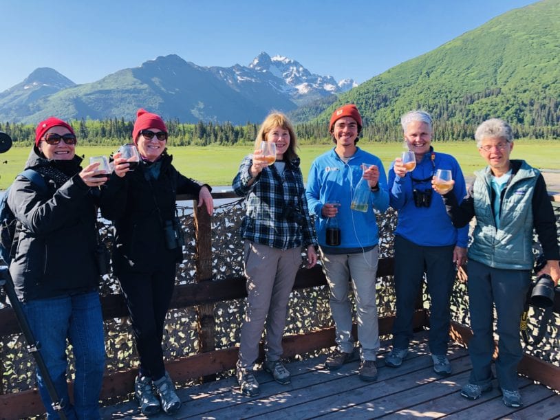 AdventureWomen celebrating on bear platform with mountains of Alaska
