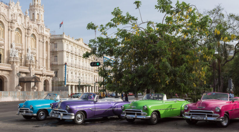 Vintage colorful American cars parked in series in Havana City with view of the gran teatro in the background