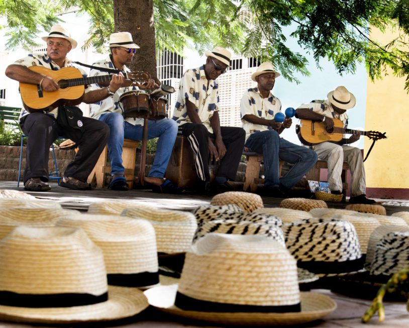 - Musicians play in front of a row of fedoras in Trinidad, Cuba