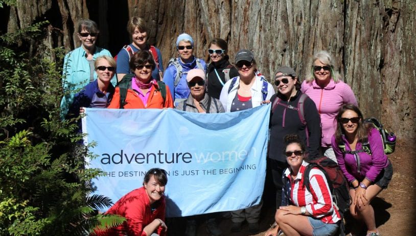 Group of Adventure Women posing with flag, in the sun with smiles