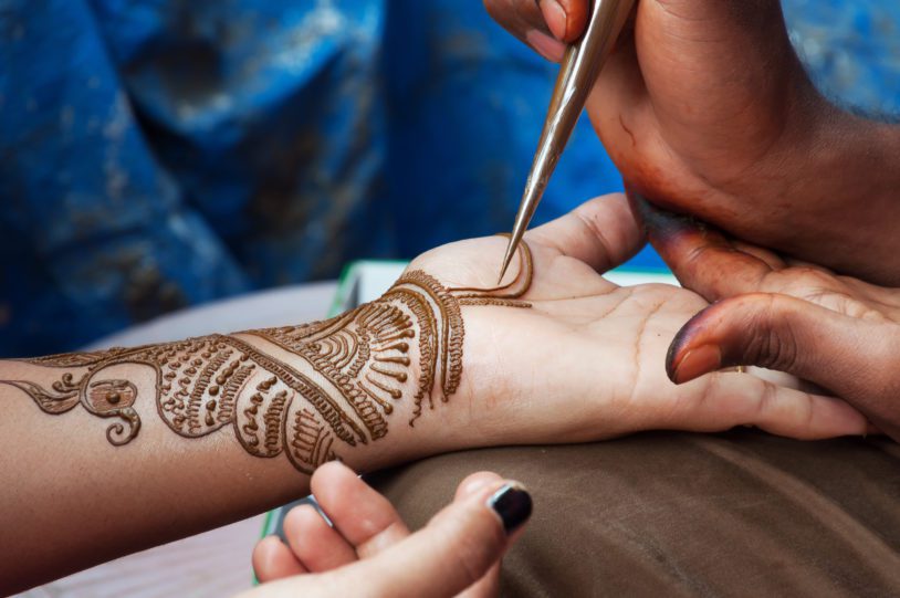 Painting Henna paste on woman's hand in the street. India