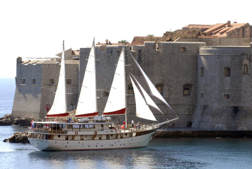 Sails open on the ship, Barbara as it passes Dubrovnik at sea along Croatia