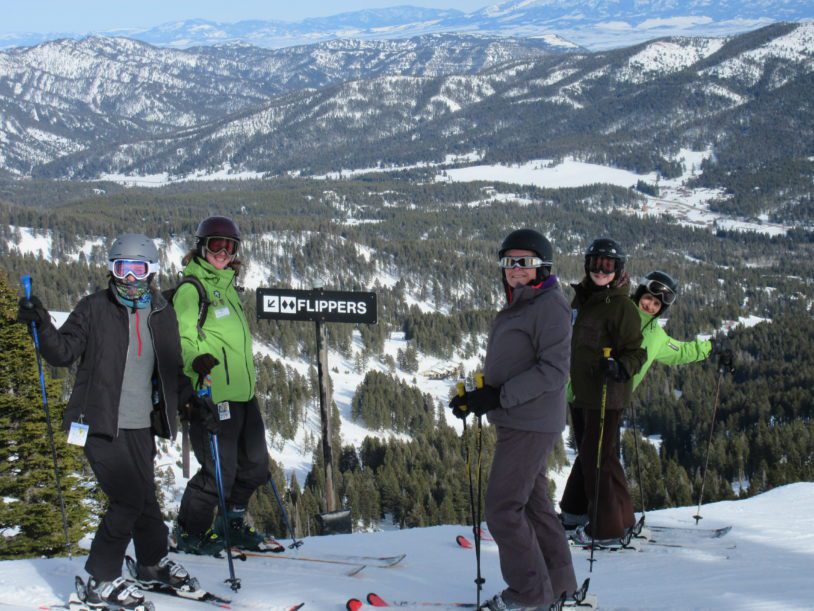 Ski instructors with guests at the top of a mountain