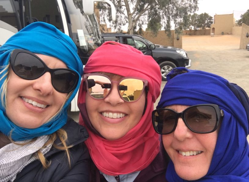 Three smiling women with color head wraps