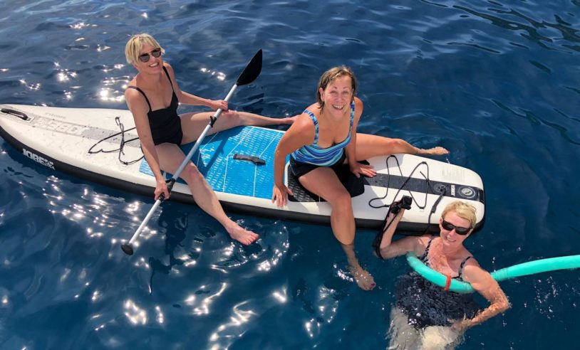 Three women floating happily on a paddleboard in the Adriatic Sea