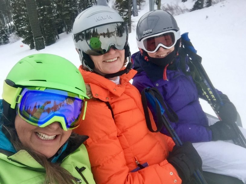 Three women in colorful ski jackets heading out for their ski lesson