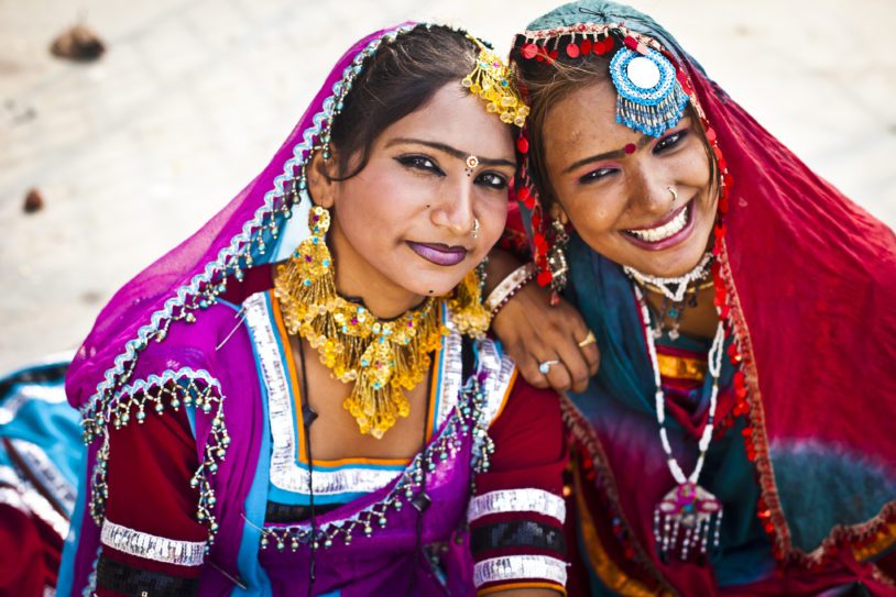Portrait of two Indian girls dressed in Rajasthani attire, laughing candidly