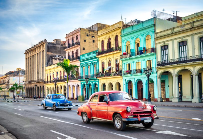 two vintage taxi cars in front of historic buildings in Old Havana, Cuba