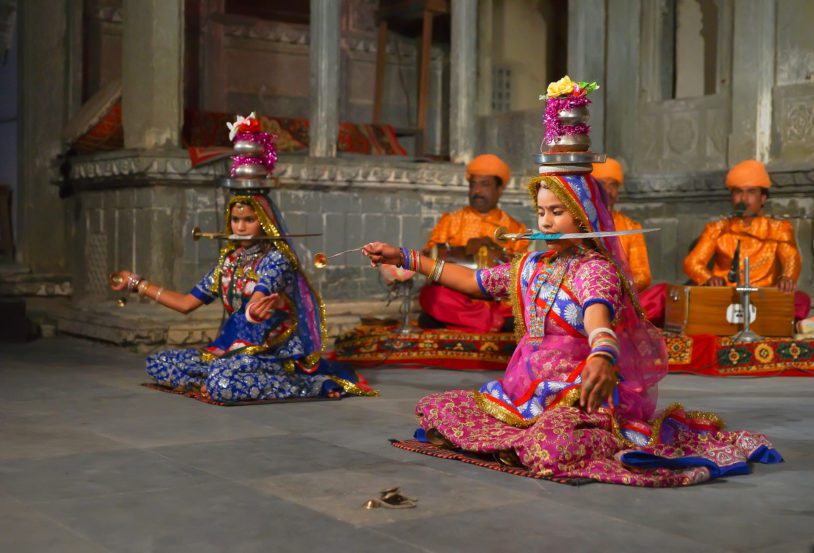An unidentified young Indian women in sari perform dance with knifes, small metal plates and pots on heads at a traditional festival sharing local Rajasthan culture in Udaipur, India