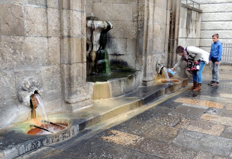 a woman filling her bottle with pure drinking water from a stone fountain
