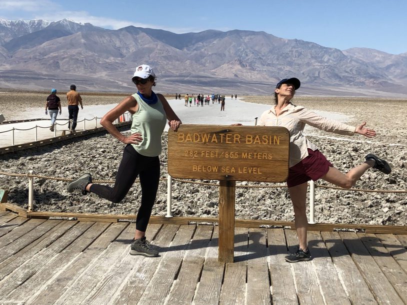 Two guests striking fun poses next to Badwater Basin sign post