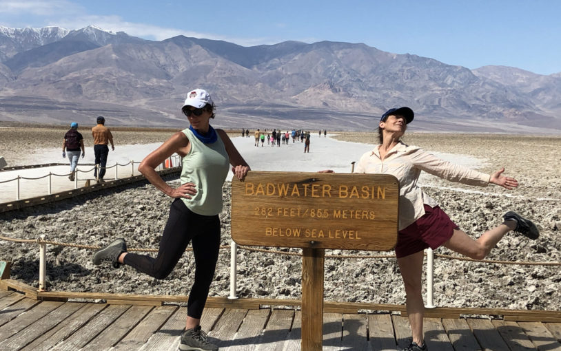Two guests striking fun poses next to Badwater Basin sign post