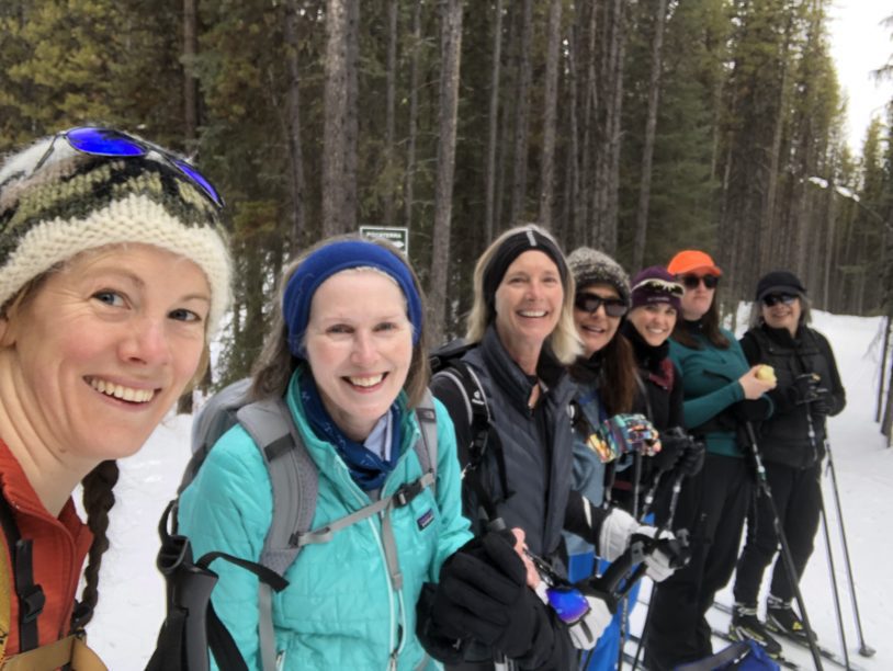 Seven women lined up smiling for a phot before skiing