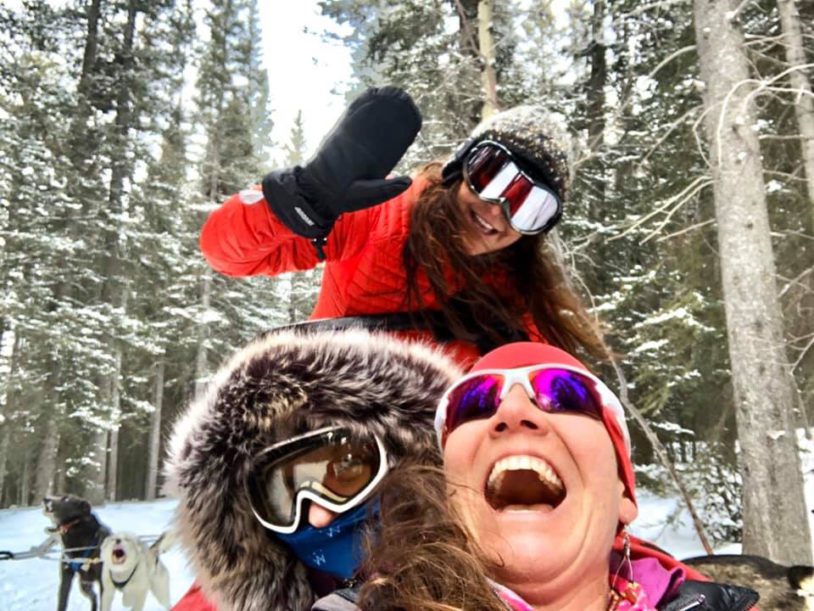 Three women laughing and having fun in winter gear in the snow