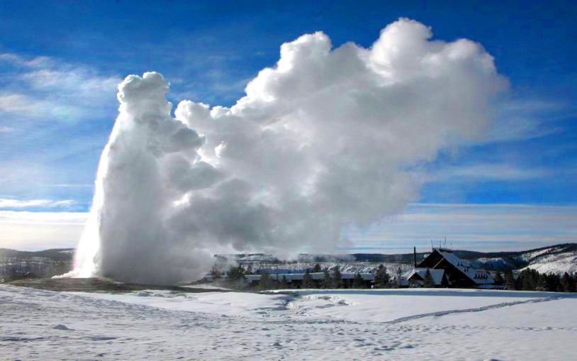 Old Faithful in winter against blue skies