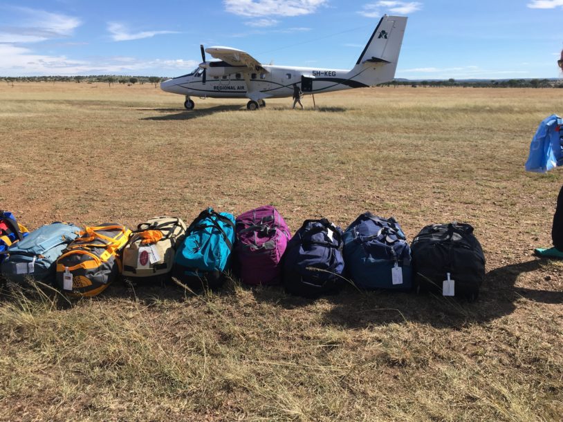 Overnight backpacks lined up next to small airplane
