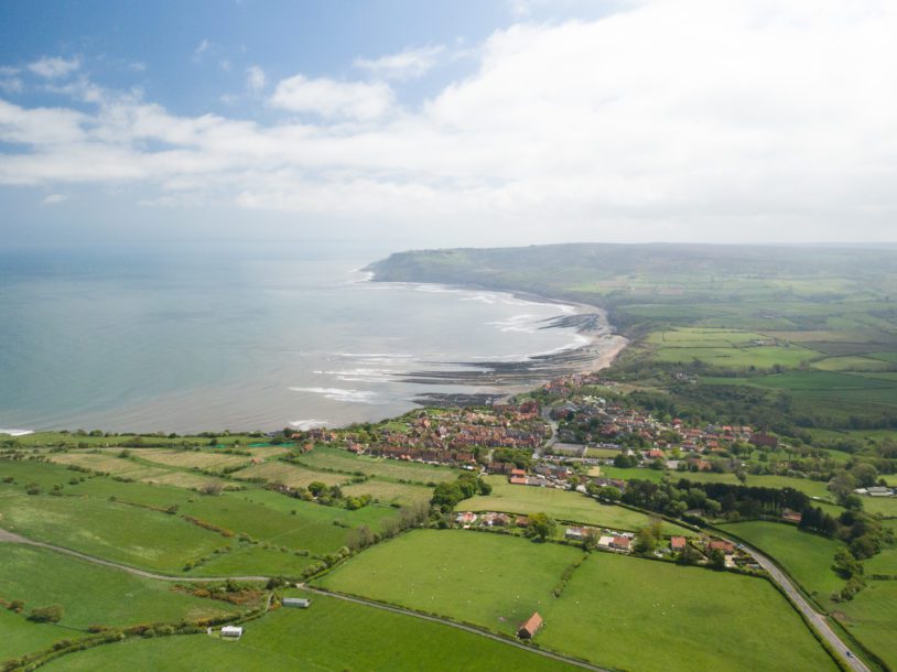 Arial shot of green pastures and Robin Hood's Bay