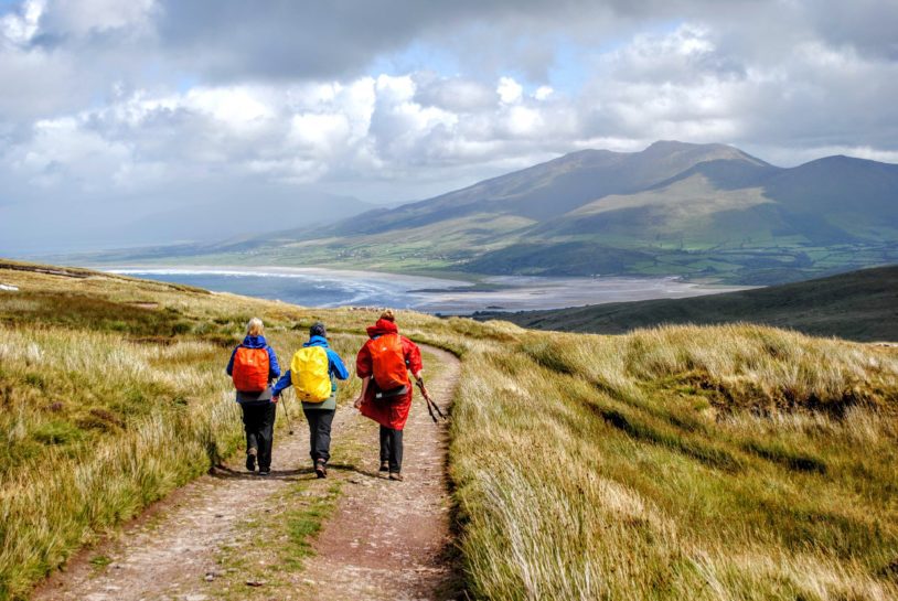 Three hikers head off onto a flat dirt road in Ireland.